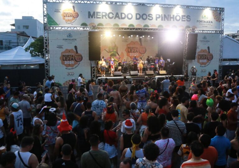Multidão de foliões no Mercado dos Pinhões durante o Carnaval de Fortaleza 2026, com música e animação.