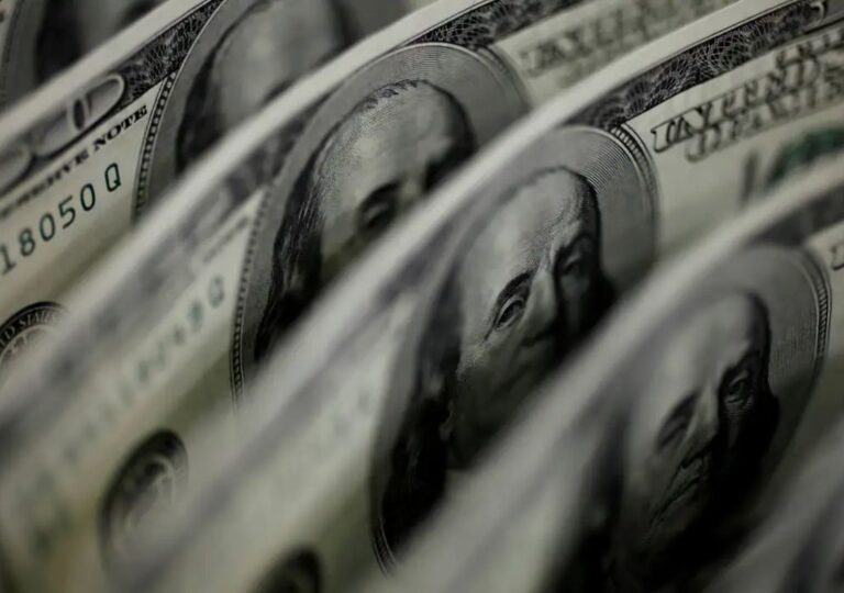 Traders monitoram telas de mercado financeiro enquanto dólar cai e bolsa bate recorde histórico