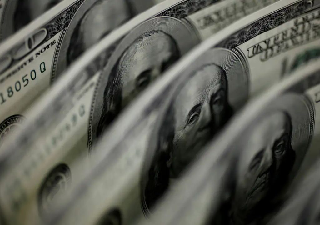 Traders monitoram telas de mercado financeiro enquanto dólar cai e bolsa bate recorde histórico