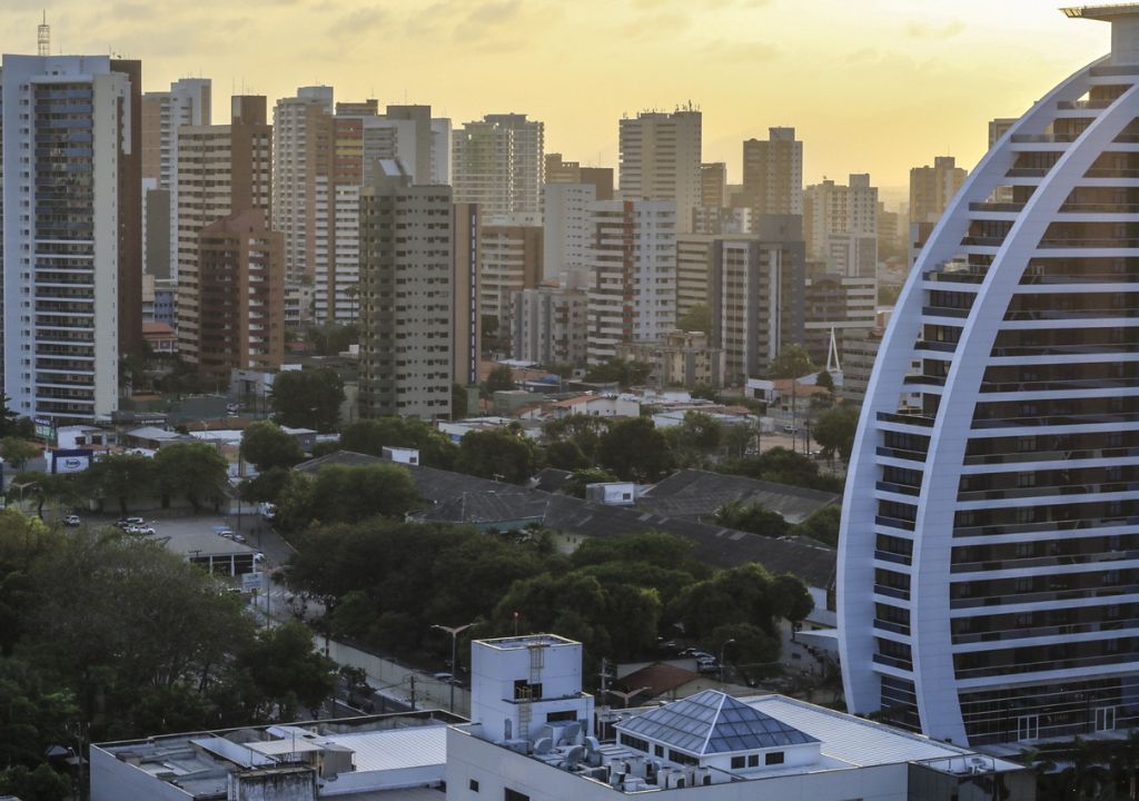 Placa “aluga-se” em prédio residencial com gráfico de queda da inflação do aluguel